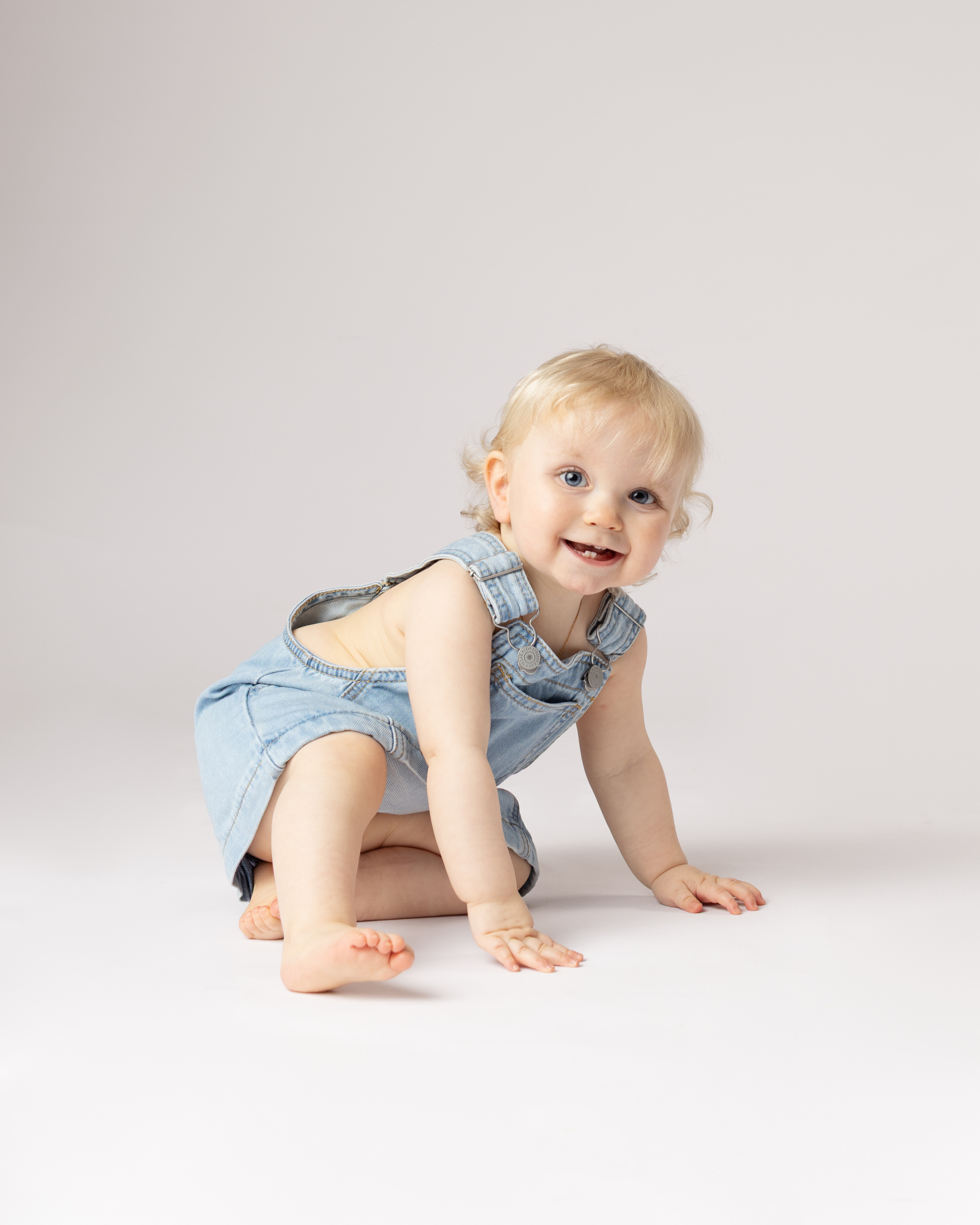 Smilende baby i dongeridress.