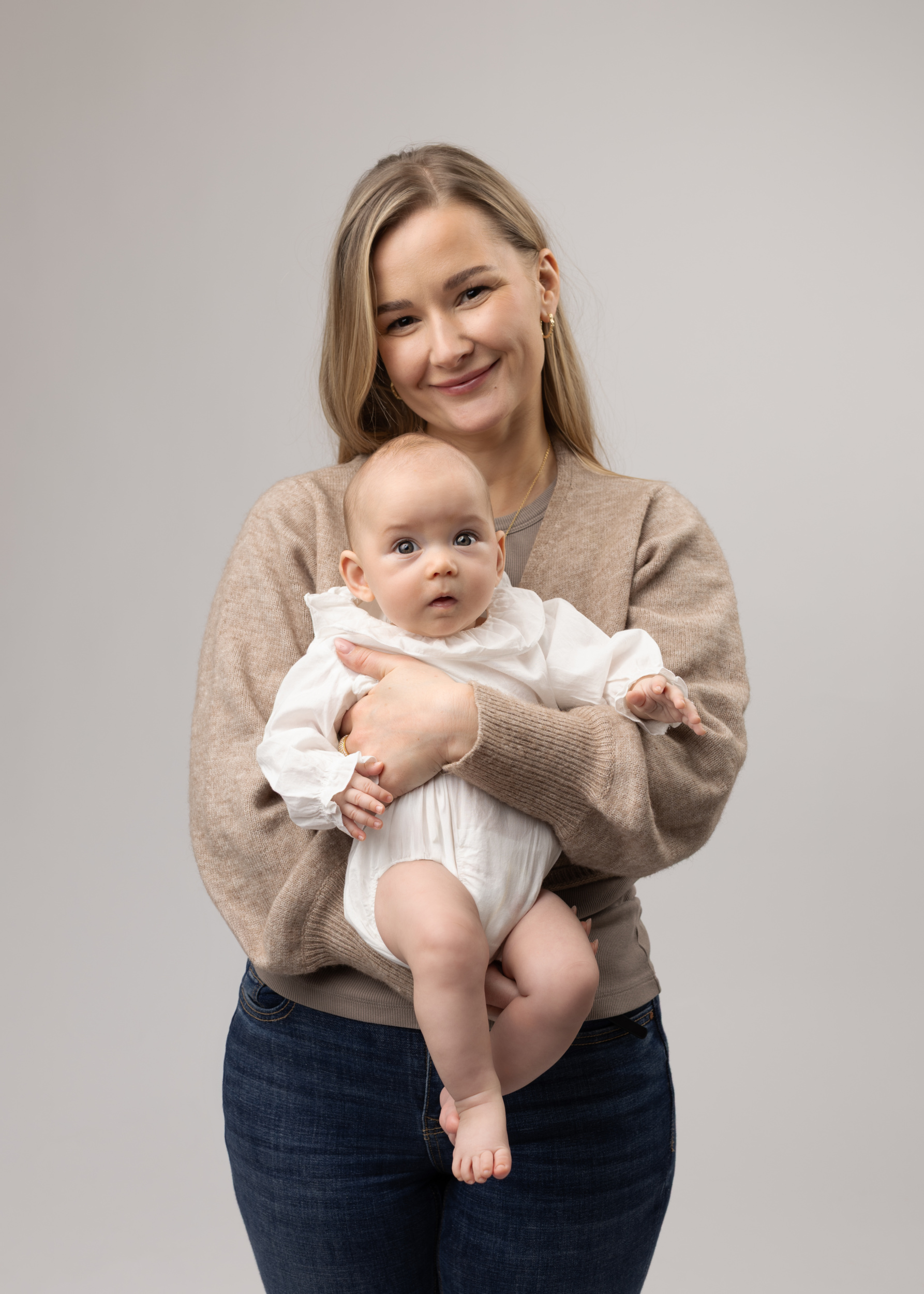 Kvinne holder baby, nøytral bakgrunn